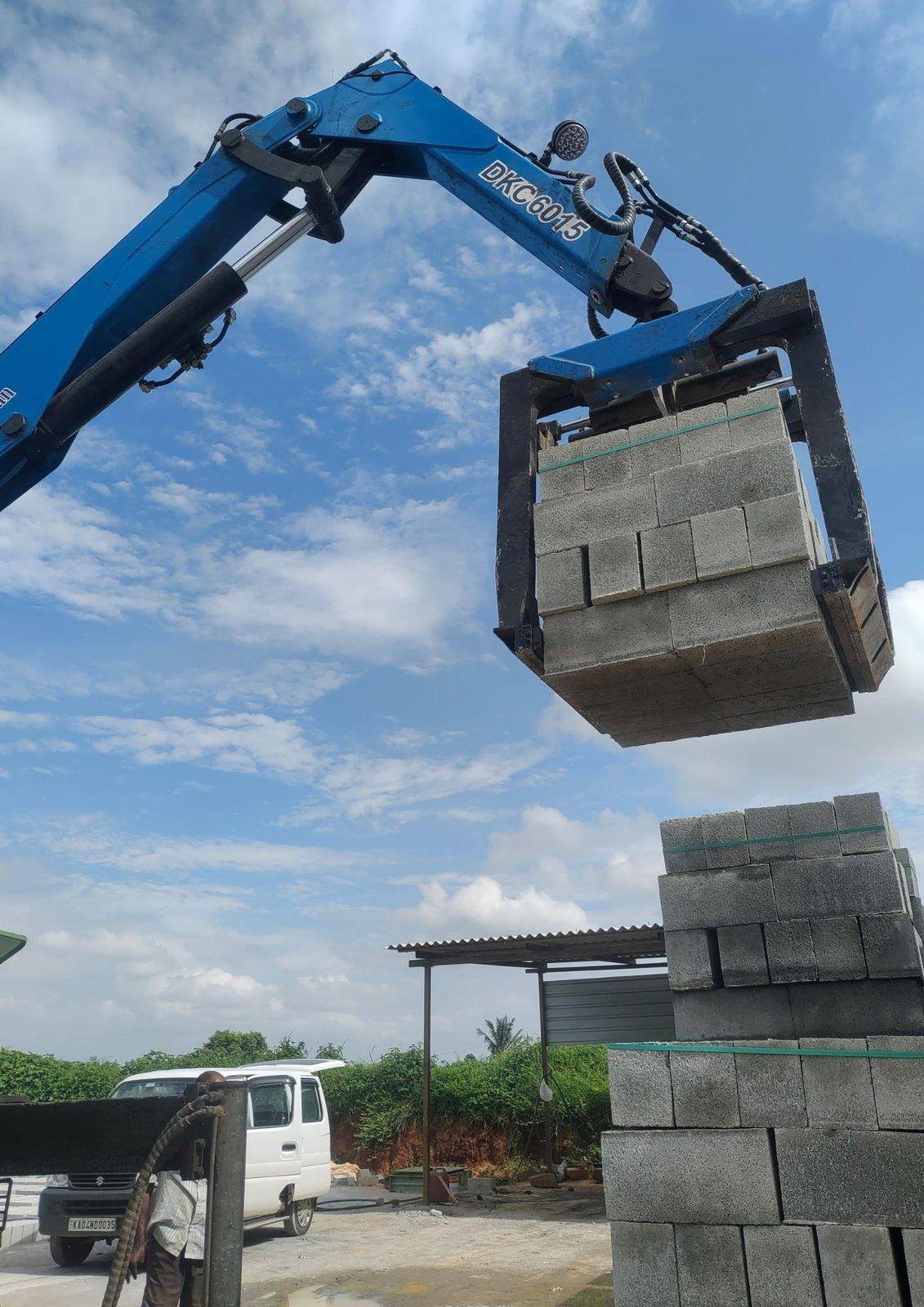 Truck-mounted crane lifting a stack of blocks with a brick grabber
