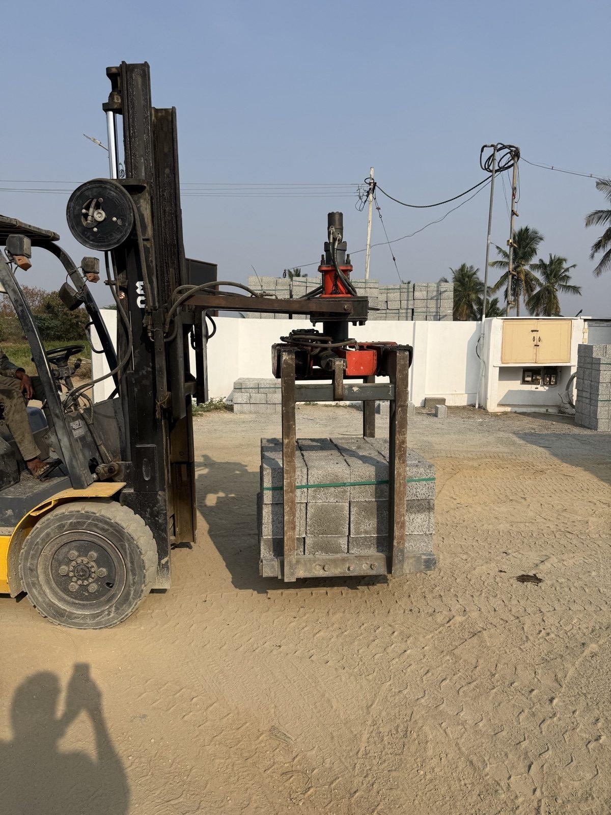 Forklift carrying a stack of paver blocks in an SAE 01 brick grabber