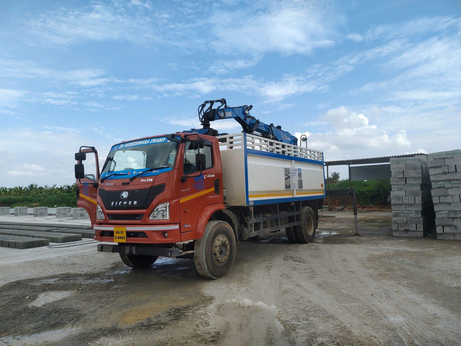 Truck-mounted knuckle boom crane beside a stack of blocks