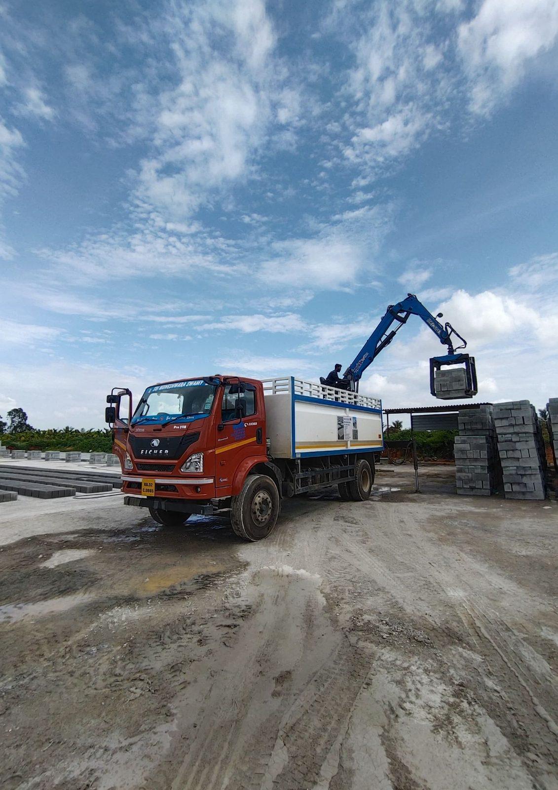 Knuckle boom crane with a grabber on a truck, working in a yard